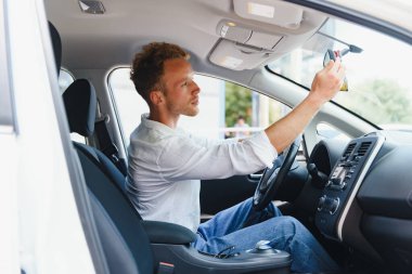 Elektrikli araba sürücüsü - yeşil enerji biyoyakıt konsepti. Direksiyondaki erkek. Yeni çevre dostu araç kullanan bir adam. Genç sahibi gururlu. Kameraya bakıyor, taksi şoförü kavramı..