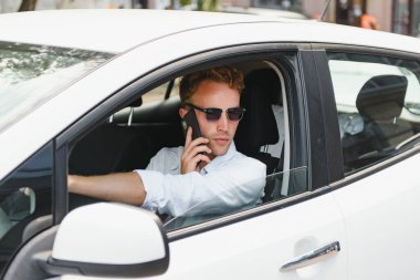 Elektrikli araba sürücüsü - yeşil enerji biyoyakıt konsepti. Direksiyondaki erkek. Yeni çevre dostu araç kullanan bir adam. Genç sahibi gururlu. Kameraya bakıyor, taksi şoförü kavramı..