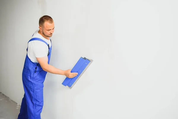 Costruttore Corregge Accuratamente Irregolarità Del Muro Con Una Spatola Costruttore — Foto Stock