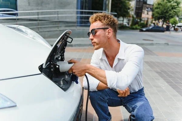 Stijlvolle Man Plaatst Stekker Van Lader Het Stopcontact Van Elektrische — Stockfoto