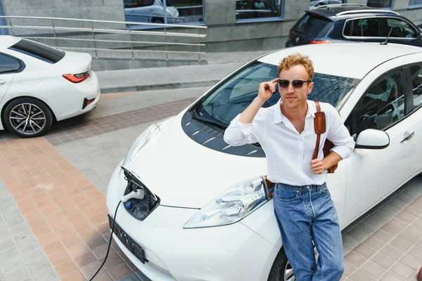 Mann Lädt Sein Luxus Elektroauto Außenstation Vor Modernen Stadtneubauten — Stockfoto