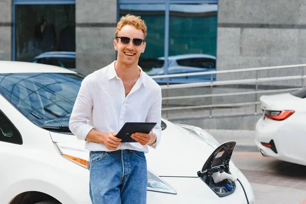 Yakışıklı Bir Genç Adam Modern Elektrikli Arabasını Şarj Ediyor — Stok fotoğraf