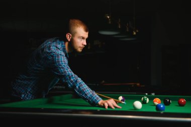 Düşünceli adam bilardo oynar. Arka planda bilardo odası..