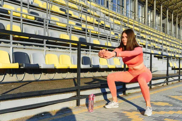 スポーツとウェルネス フィットネスの女の子がワークアウトをストレッチ 強い筋肉ボディトレーニングとファッションスポーティな女性 屋外スタジアムで女性のストレッチフィット — ストック写真