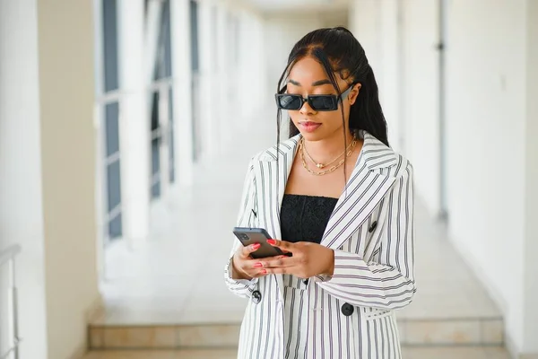 African-American businesswoman speaking by smartphone in office hall, copy space