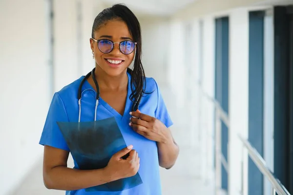 医療の概念 病院の背景に聴診器で白いコートで幸せな笑顔アフリカ系アメリカ人女性医師 — ストック写真