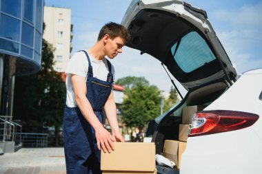 Teslimatçı paketleri arabada tutuyor, teslimat yapıyor.