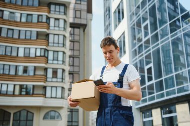 Teslimat servisi arabasının yanında paketleri olan genç bir erkek kurye.
