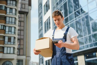 Üniformalı kurye paketi ve telefonu tutuyor.