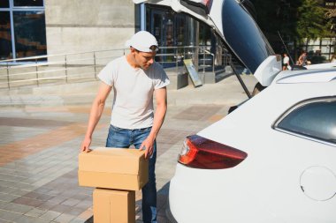 Teslimatçı, arabadan kutuyu alıyor..
