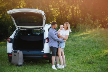 Güneşli bir günde bagajın yanında mutlu bir aile. Yolculuk