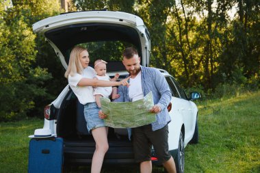 Genç bir aile. Beyaz elbiseli üç kişi piknik yapıyor. Güzel ebeveynler ve kızlar yaz tatilinde arabayla seyahat ederler. Parkta Sahne