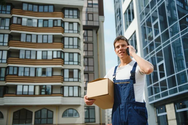 Üniformalı kurye paketi ve telefonu tutuyor.