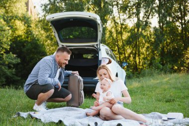 Ormandaki aile. İnsanlar arabanın yanında. Gün batımı arkaplanı.