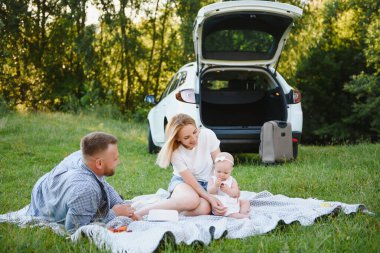 Ormandaki aile. İnsanlar arabanın yanında. Gün batımı arkaplanı.
