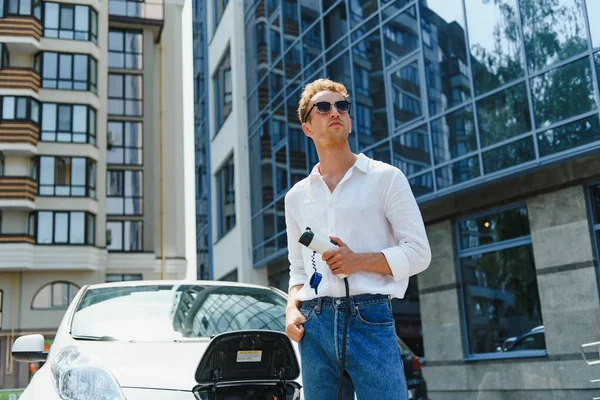 Homem Carregando Seu Carro Elétrico Luxo Estação Livre Frente Edifícios — Fotografia de Stock