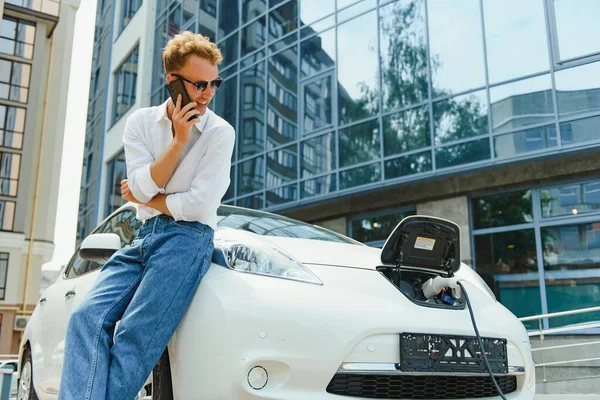 Schöner Mann Benutzt Handy Während Das Auto Geladen Wird — Stockfoto