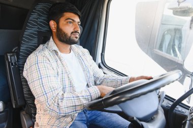 Genç Hintli bir adam ticari bir kamyon kullanıyor, malları taşıyor. Lojistik yolculuğunu odaklanmış profesyonel kontrol