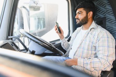 Kamyon şoförü takside oturmuş telefona bakıyor. Dikkati dağılmış ve güvensiz sürücüyü temsil ediyor.