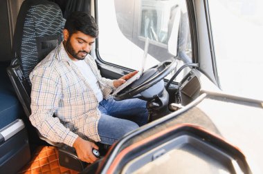 Genç adam ticari aracının içinde bir bilgisayar kullanıyor, lojistiği yönetiyor ve yolda bağlı kalıyor.