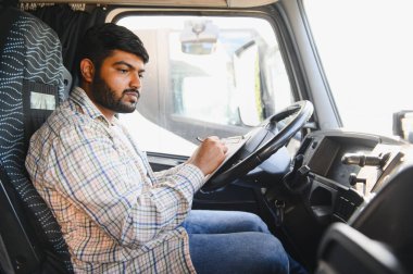 Profesyonel Hintli erkek kamyon şoförü, taksinin içinde dokümanları inceliyor, lojistiği yönetiyor.