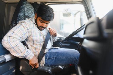 Erkek kamyon şoförü emniyet kemerini taksinin içinde emniyete alıyor, ulaşım güvenliği ve sorumlu sürüş üzerine vurgu yapıyor.