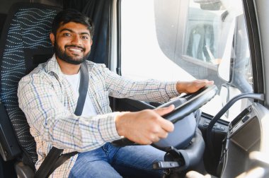 Kamyon şoförü olarak çalışan gülümseyen genç Hintli adam takside oturmuş ve direksiyonu tutuyordu.