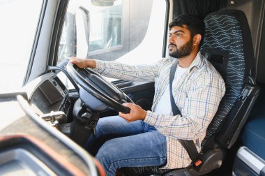 Hintli şoför emniyet kemeri takıyor, takside oturuyor, elleri direksiyonda, uzun mesafeli taşımaya hazır.