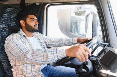 Hintli erkek sürücü büyük bir araç kullanıyor, yola odaklanıyor, lojistik ve teslimat hizmetleri sağlıyor.