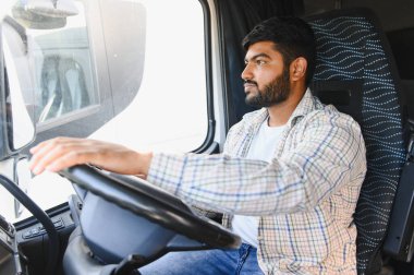 Ekose gömlekli bir adam büyük bir ticari kamyon kullanıyor. Ulaşım, lojistik ve profesyonel sürüş temsilcisi.