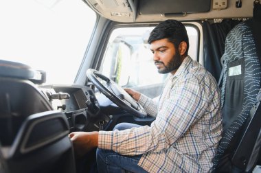 Profesyonel bir adam ticari kamyon kulübesinde oturuyor, elleri direksiyonda ve kontakta, teslimata hazırlanıyor.