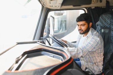 Hintli adam büyük bir kamyon kargo aracı kullanıyor. Lojistik ve nakliye sektöründe çalışan profesyonel kamyon şoförü.