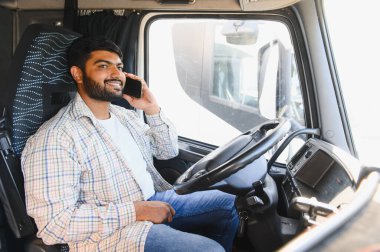 Gülümseyen Hintli adam ağır bir araç kullanıyor ve bir telefon görüşmesiyle meşgul, iş ya da aile ile yolda bağlantı kuruyor.