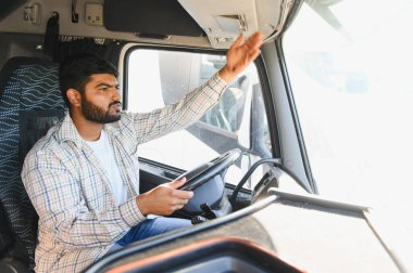 Profesyonel Hintli genç adam ağır bir araç kullanıyor, direksiyonu kontrol ediyor ve taksiyle etkileşime geçiyor.