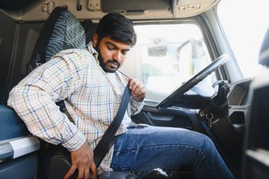 Ticari araç kulübesinde genç bir adam emniyet kemerini takıyor, taşımacılığa başlamadan önce güvenliği sağlıyor.