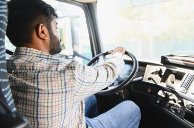 Genç adam ticari bir kamyon kullanıyor, elleri direksiyonda, malları teslim ediyor, ulaşım ve lojistiği gösteriyor.