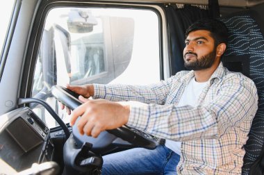 Kamaradaki profesyonel kamyon şoförü, direksiyon tutarken ileri bakıyor, ağır araç kullanıyor.