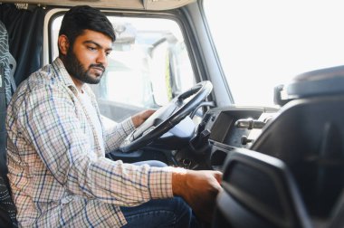 Genç Hintli bir kamyon şoförü. Ulaşım ve lojistik bölümünde çalışıyor. Kamyon kabininde oturuyor.