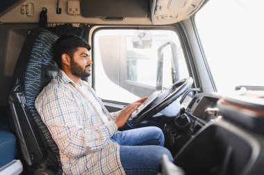 Hintli sürücü bir kamyon kabininde modern bir tablet kullanıyor, lojistik ve ulaşım görevlerini yönetiyor.