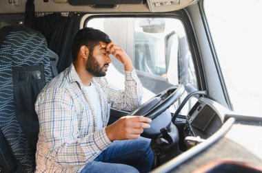 Hintli adam araba kullanırken stres ve yorgunluk yaşıyor. Kamyon kabininde alnı üzerinde dinleniyor.