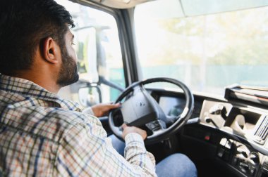 Hintli bir adam otobanda büyük bir kamyon sürüyor, önündeki yola odaklanıyor. Malların taşınması, profesyonel bir uğraş.