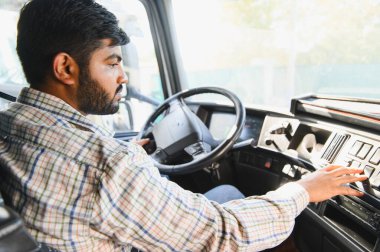 Ticari kamyon süren Hintli bir adam, gösterge panelini ayarlıyor, ulaşım endüstrisini ve mesleki mesleği temsil ediyor.
