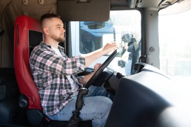Yarı kamyon süren, direksiyonu kullanan genç bir adam. Çalışma, ulaşım ve teslimat kavramlarına odaklanma