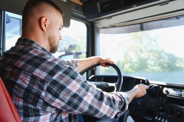 Profesyonel kamyon şoförü kabinin içinde direksiyon başında, lojistik ve ulaşım için araba kullanıyor.