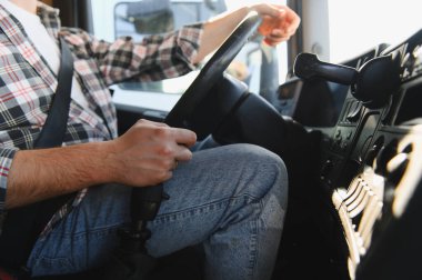 Bir adam güvenli taşımacılığa ve teslimata odaklanmış bir şekilde yolculuğu boyunca bir kamyonu sürüyor. Lojistik sektörü çalışanını temsil ediyor.