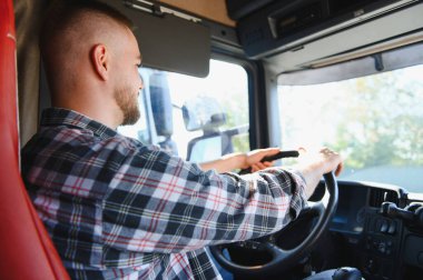 Yolda kamyon süren adam, işine odaklanmış, malları lojistik ve teslimat yoluyla taşıyor.