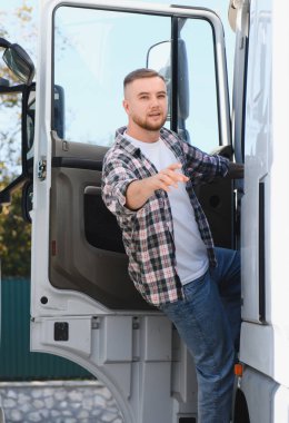 Genç şoför kamyon kulübesinden ayrılıyor, ileriye bakıyor. Ulaşım, lojistik ve profesyonel sürüş