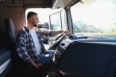 Profesyonel kamyon şoförü gülümsüyor, ağır araç taksisinde oturuyor, uzun mesafeli taşımayı bekliyor.