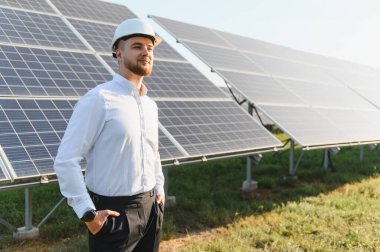 Mühendis, yenilenebilir enerji, sürdürülebilirlik ve yeşil teknoloji çözümlerini sembolize ederek, büyük güneş dizisi tarafından güvenle ayakta duruyor.