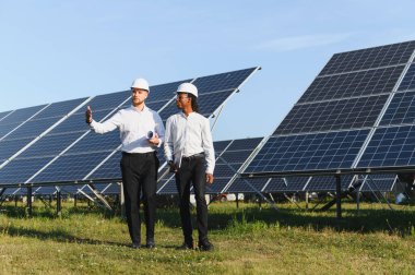 Bir güneş çiftliğinde yenilenebilir enerji çözümlerini tartışan iki farklı mühendis, takım çalışmasını ve sürdürülebilir enerji üretimini vurguluyor